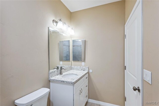 bathroom featuring baseboards, vanity, and toilet