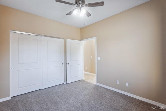 unfurnished bedroom with ceiling fan, carpet floors, a closet, and baseboards