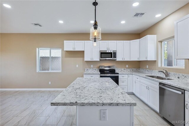 kitchen with stainless steel appliances, visible vents, a sink, and a kitchen island