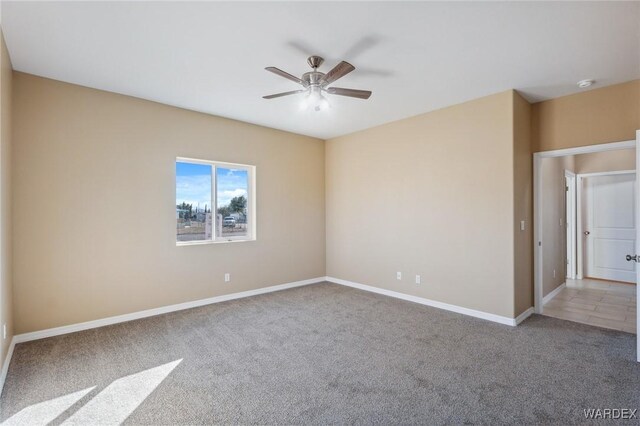 empty room featuring carpet flooring, a ceiling fan, and baseboards