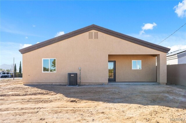 back of house featuring fence, central AC, and stucco siding