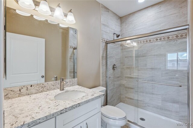 bathroom with toilet, a shower stall, and vanity