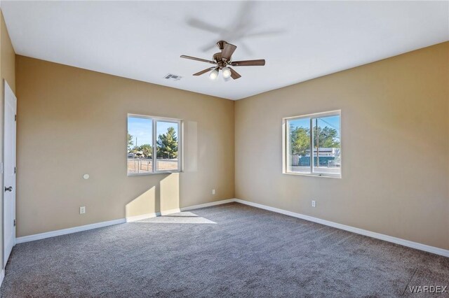 empty room with ceiling fan, carpet flooring, visible vents, and a healthy amount of sunlight