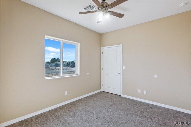 carpeted empty room with visible vents, baseboards, and ceiling fan