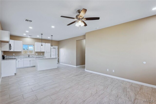 kitchen featuring visible vents, white cabinets, a kitchen island, open floor plan, and light countertops