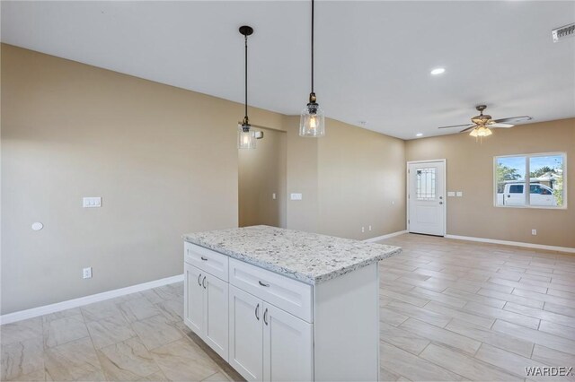 kitchen with hanging light fixtures, a kitchen island, white cabinetry, and baseboards