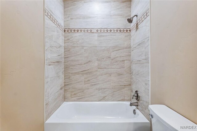 bathroom featuring tub / shower combination and toilet