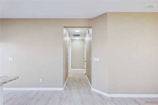 hallway featuring visible vents and baseboards