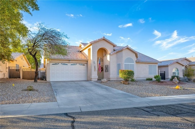 mediterranean / spanish home with a garage, concrete driveway, a tiled roof, fence, and stucco siding