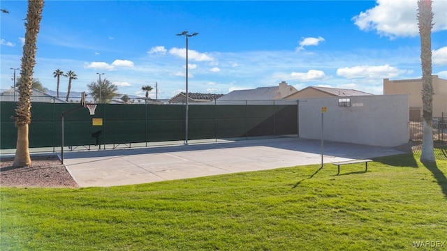 view of basketball court with a yard and fence