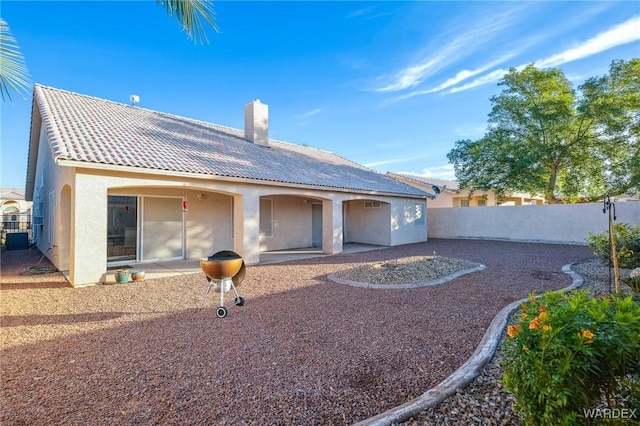 back of property featuring a patio, a chimney, stucco siding, fence, and a tiled roof