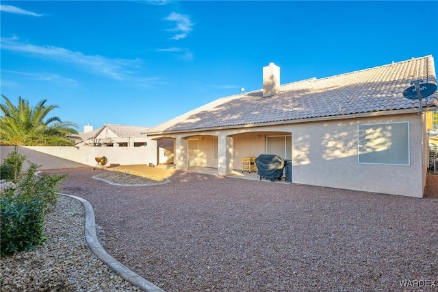 rear view of house with a patio, a fenced backyard, a chimney, a tiled roof, and stucco siding