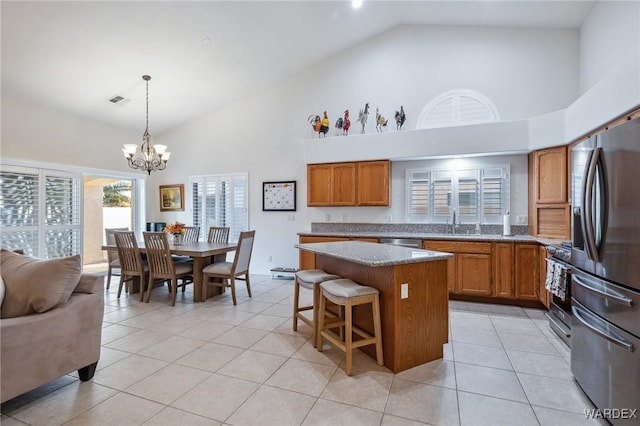 kitchen with stainless steel appliances, brown cabinetry, a kitchen island, and hanging light fixtures