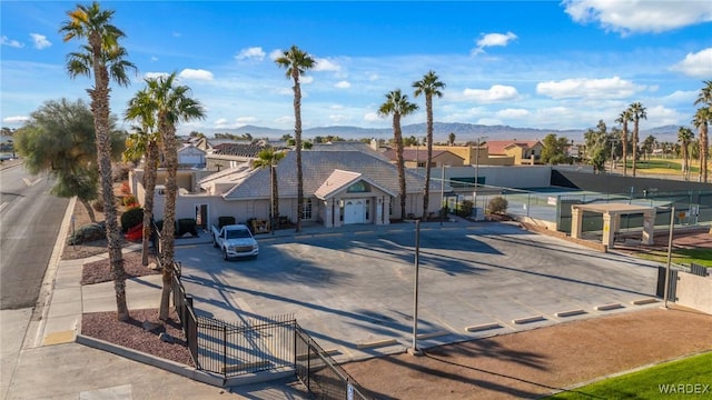 view of front of home with a tennis court, a residential view, fence, and a mountain view