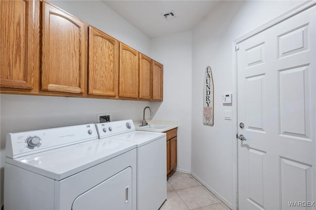 washroom with light tile patterned floors, a sink, visible vents, cabinet space, and washing machine and clothes dryer