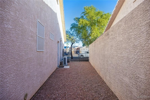 view of side of home with central air condition unit, fence, and stucco siding