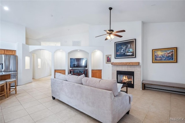 living area with visible vents, arched walkways, a tile fireplace, ceiling fan, and light tile patterned flooring