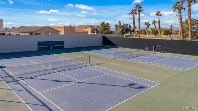 view of tennis court featuring community basketball court, fence, and a residential view