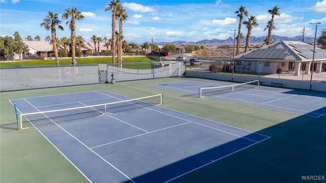 view of tennis court featuring fence and a mountain view