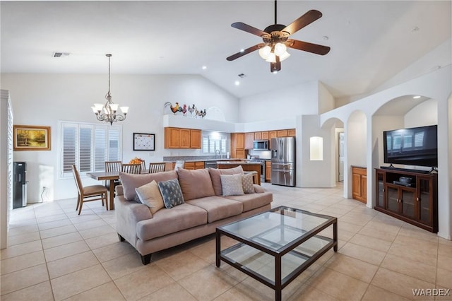 living room with high vaulted ceiling, ceiling fan with notable chandelier, visible vents, and light tile patterned flooring