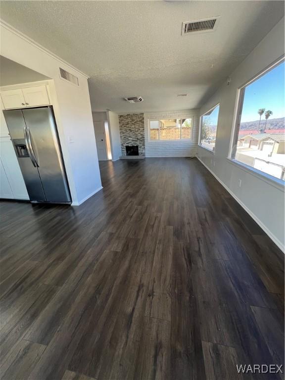 unfurnished living room with visible vents, a fireplace, and a textured ceiling