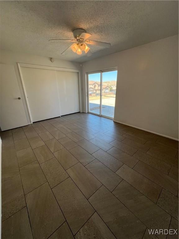 unfurnished bedroom featuring access to outside, a closet, a ceiling fan, and a textured ceiling