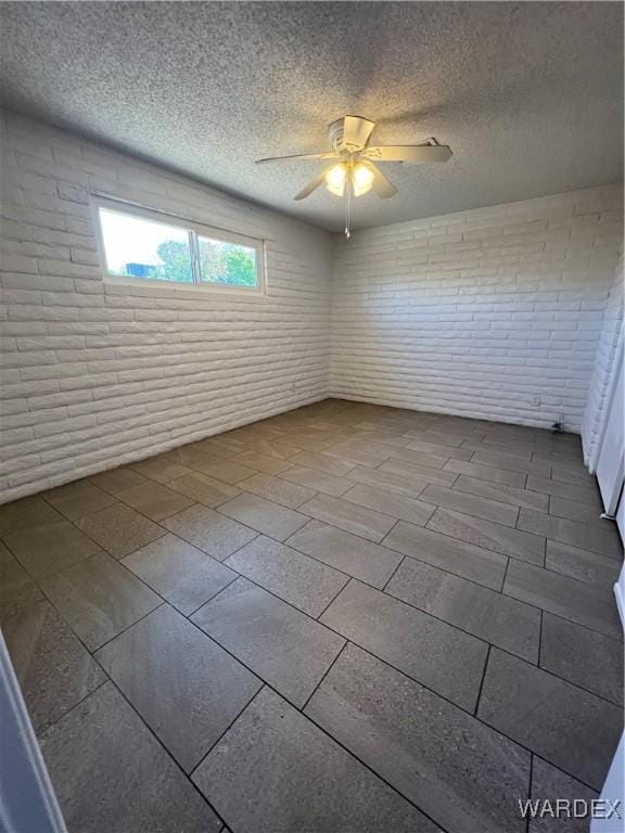 unfurnished room with a textured ceiling, brick wall, and a ceiling fan