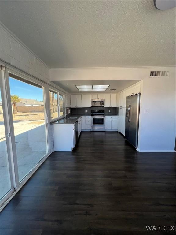 kitchen with visible vents, white cabinets, stainless steel appliances, crown molding, and a sink