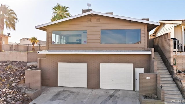 view of front of home with brick siding, concrete driveway, a garage, and fence