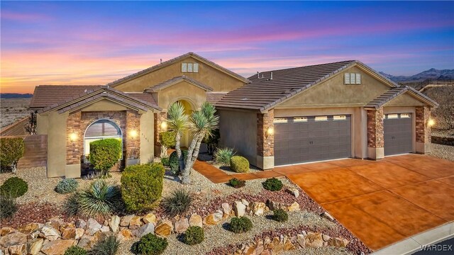 view of front of home featuring stone siding, driveway, an attached garage, and stucco siding