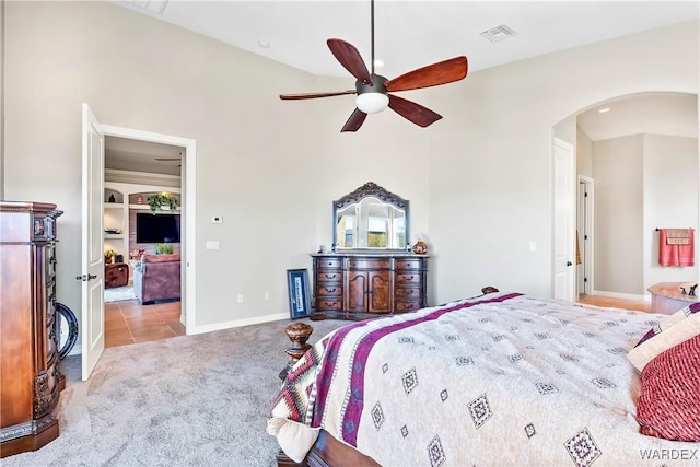 bedroom with light carpet, visible vents, arched walkways, baseboards, and ceiling fan