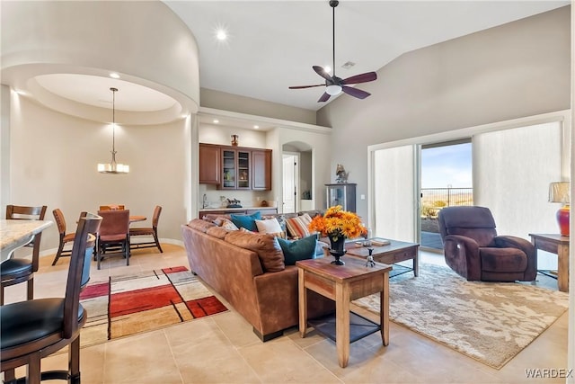 living room featuring arched walkways, high vaulted ceiling, light tile patterned floors, ceiling fan with notable chandelier, and baseboards