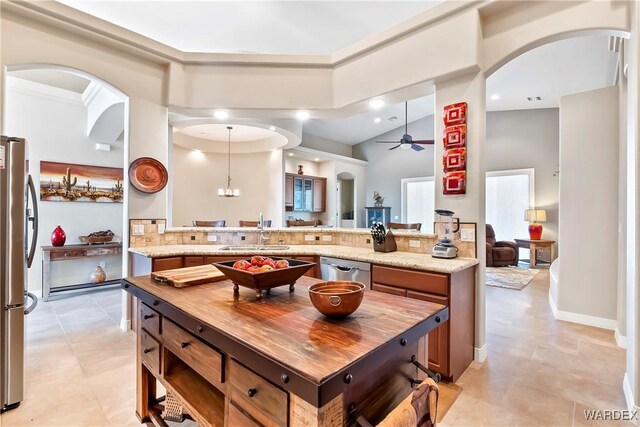 kitchen featuring a peninsula, a sink, light stone countertops, and stainless steel appliances