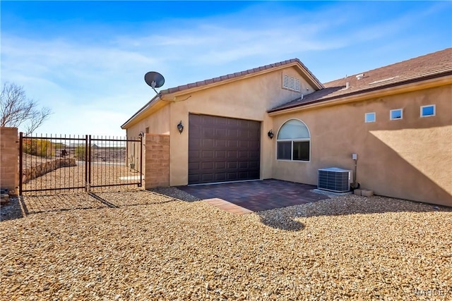 view of home's exterior featuring central air condition unit, an attached garage, fence, and stucco siding