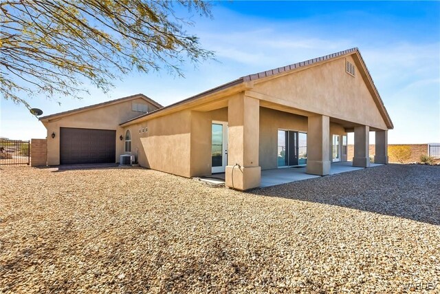 rear view of property with a patio, stucco siding, an attached garage, central AC, and fence