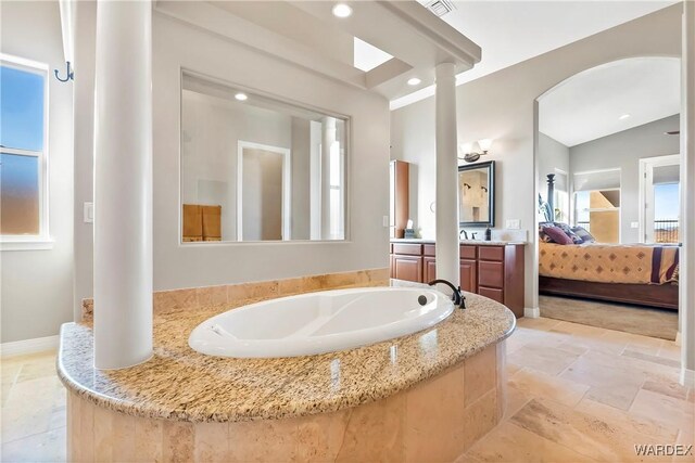 full bathroom featuring recessed lighting, stone tile floors, vanity, baseboards, and ensuite bath