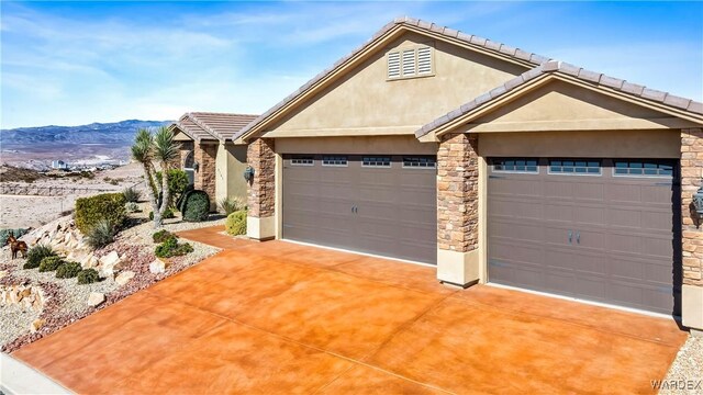 view of front of property with stone siding, an attached garage, a mountain view, and stucco siding