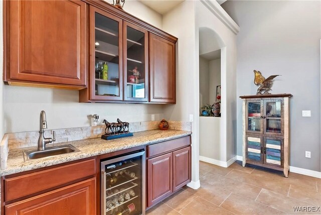 bar featuring wine cooler, indoor wet bar, light tile patterned floors, a sink, and baseboards