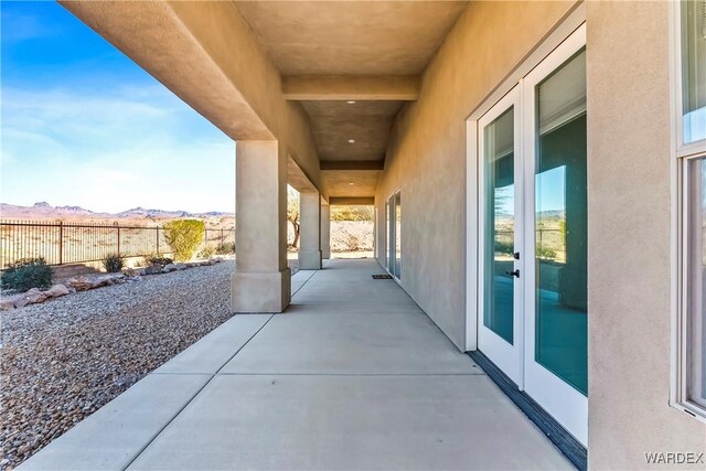 view of patio featuring fence, a mountain view, and french doors