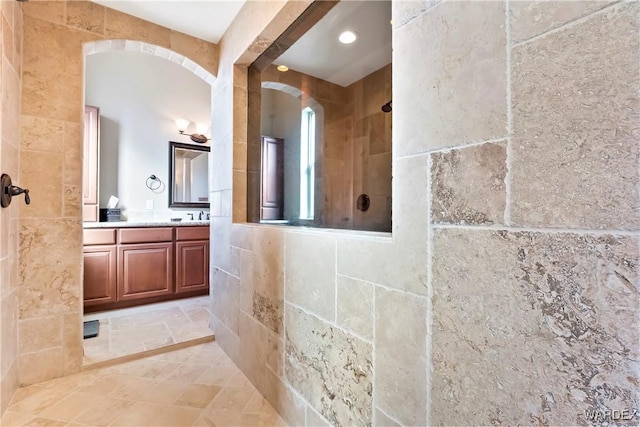 bathroom with a tile shower and vanity