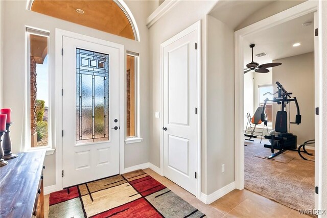 foyer entrance featuring baseboards, light tile patterned floors, visible vents, and light colored carpet