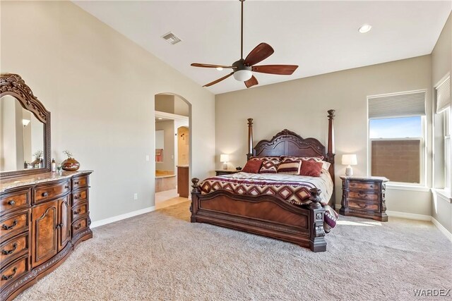 bedroom featuring light carpet, baseboards, visible vents, arched walkways, and ensuite bathroom