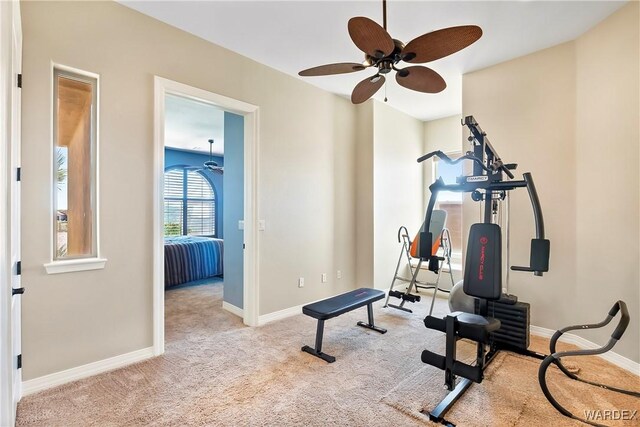 workout room featuring baseboards, ceiling fan, and light colored carpet