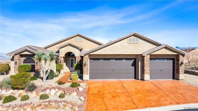 view of front of house with an attached garage, stone siding, concrete driveway, a tiled roof, and stucco siding