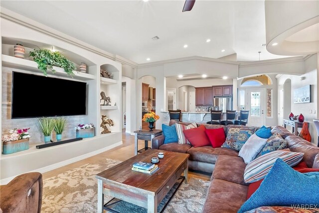 living room featuring built in shelves, arched walkways, visible vents, and recessed lighting