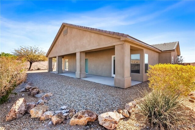 view of home's exterior with a patio area, a tile roof, and stucco siding