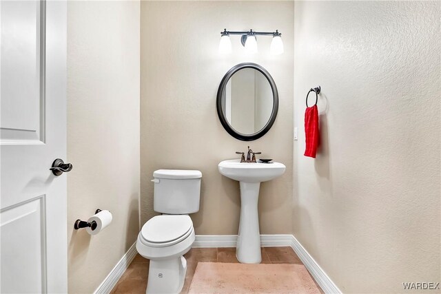 bathroom with toilet, tile patterned flooring, baseboards, and a sink