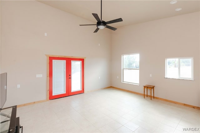 empty room with high vaulted ceiling, french doors, ceiling fan, and baseboards