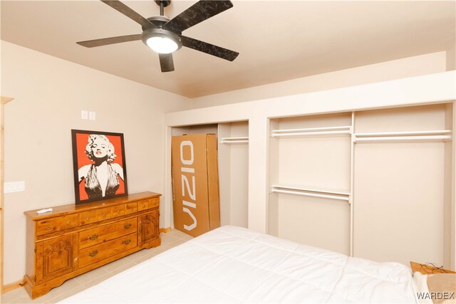 bedroom with ceiling fan, light tile patterned floors, and two closets