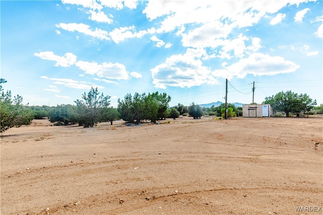 view of yard with a rural view, an outdoor structure, and a storage shed